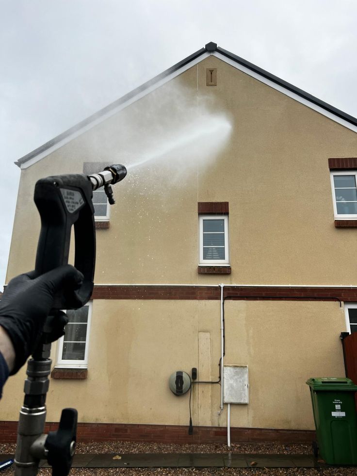 Artisan nettoyant une façade de maison avec lance haute pression